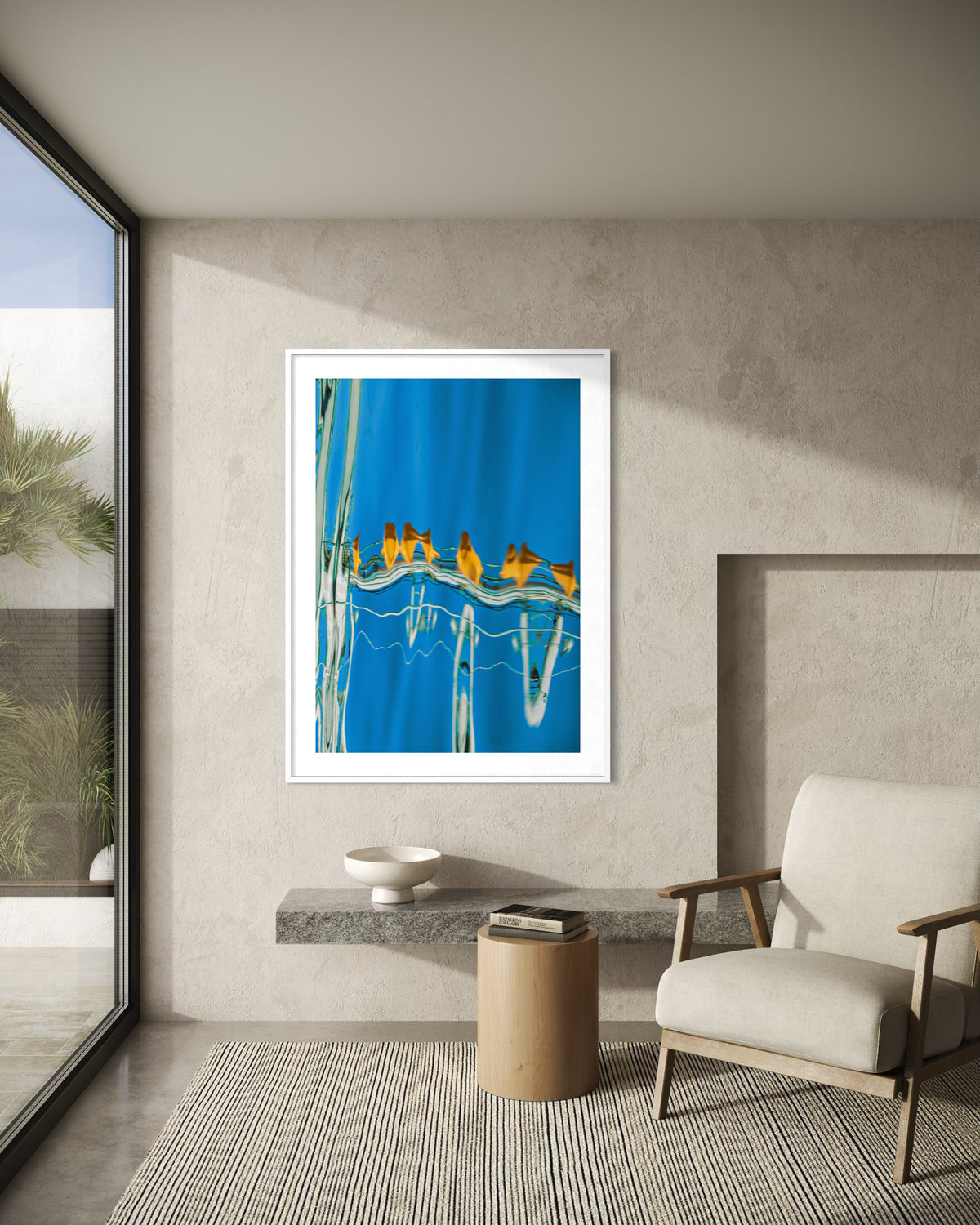 The Water Ballet by Ralph Kerle, in situ, framed on a textured wall beside an armchair and a large window.