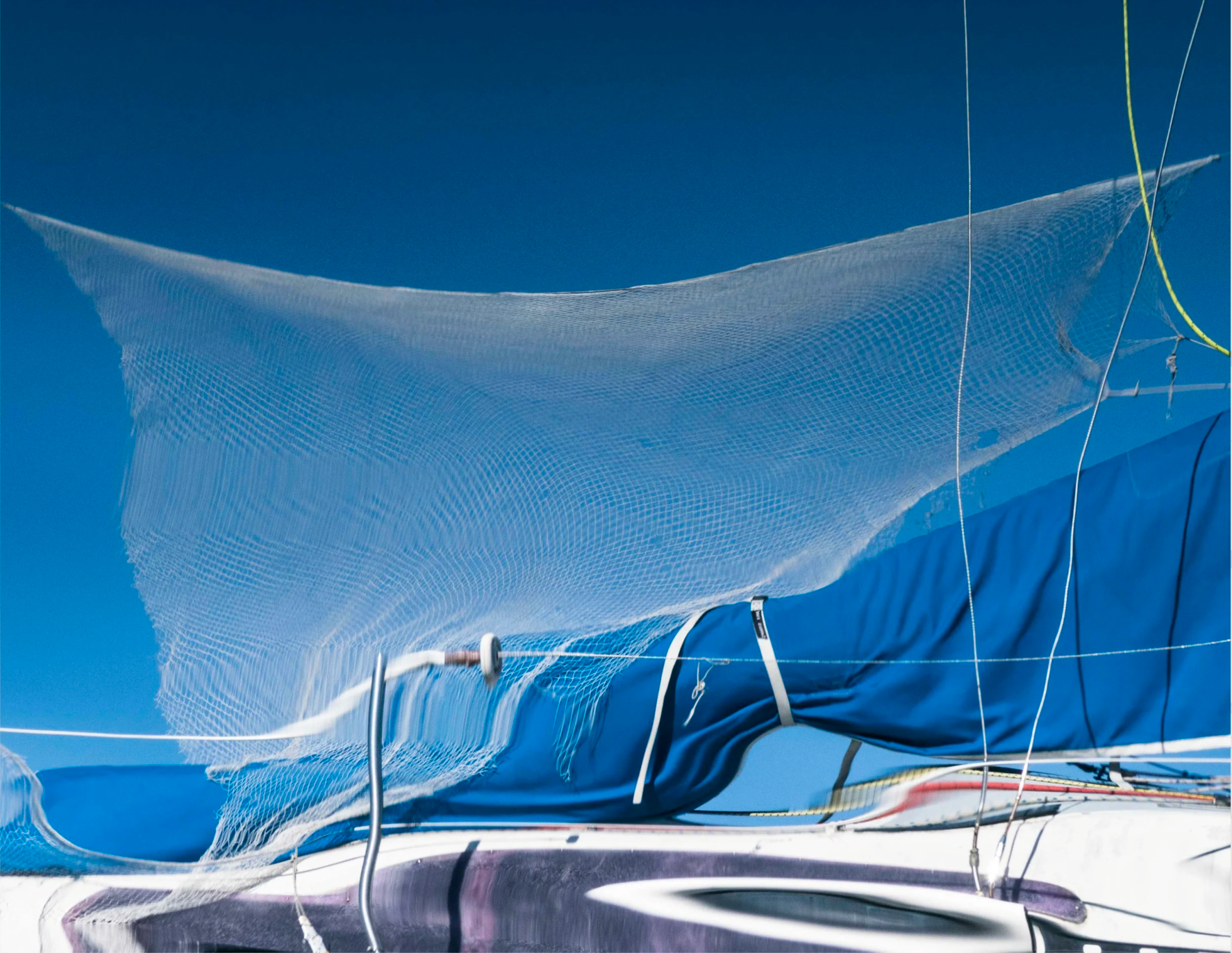 Fishing net draped over a boat against a clear blue sky