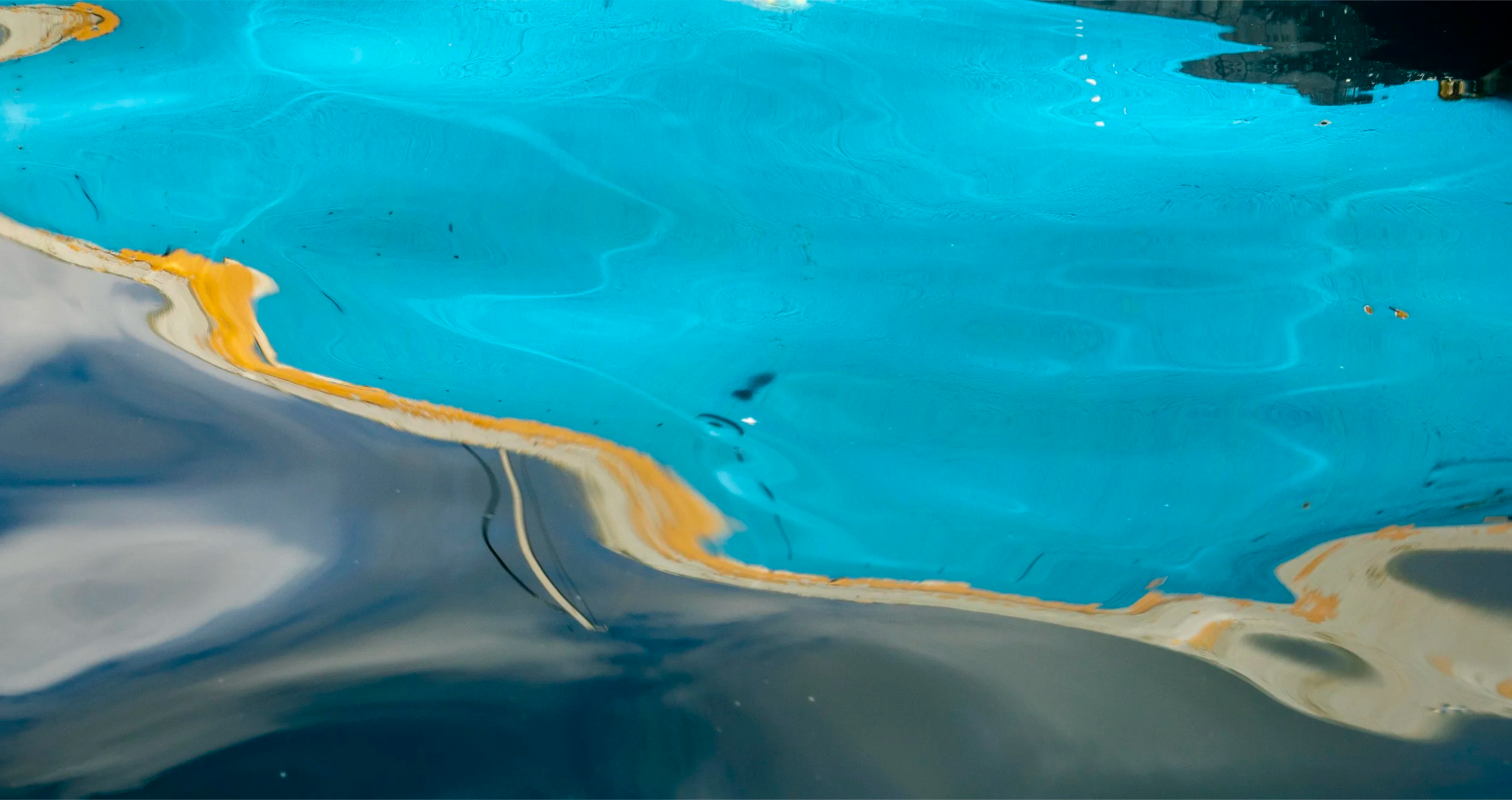 Close-up of a pool with blue water and visible rust or algae growth on the bottom.