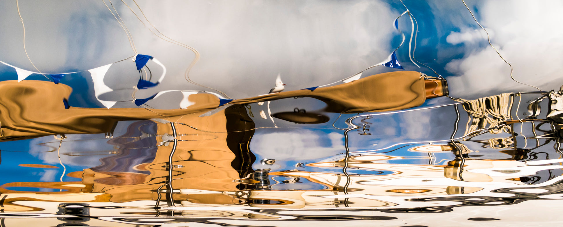 Reflective surface with gold object and blue sky with clouds.