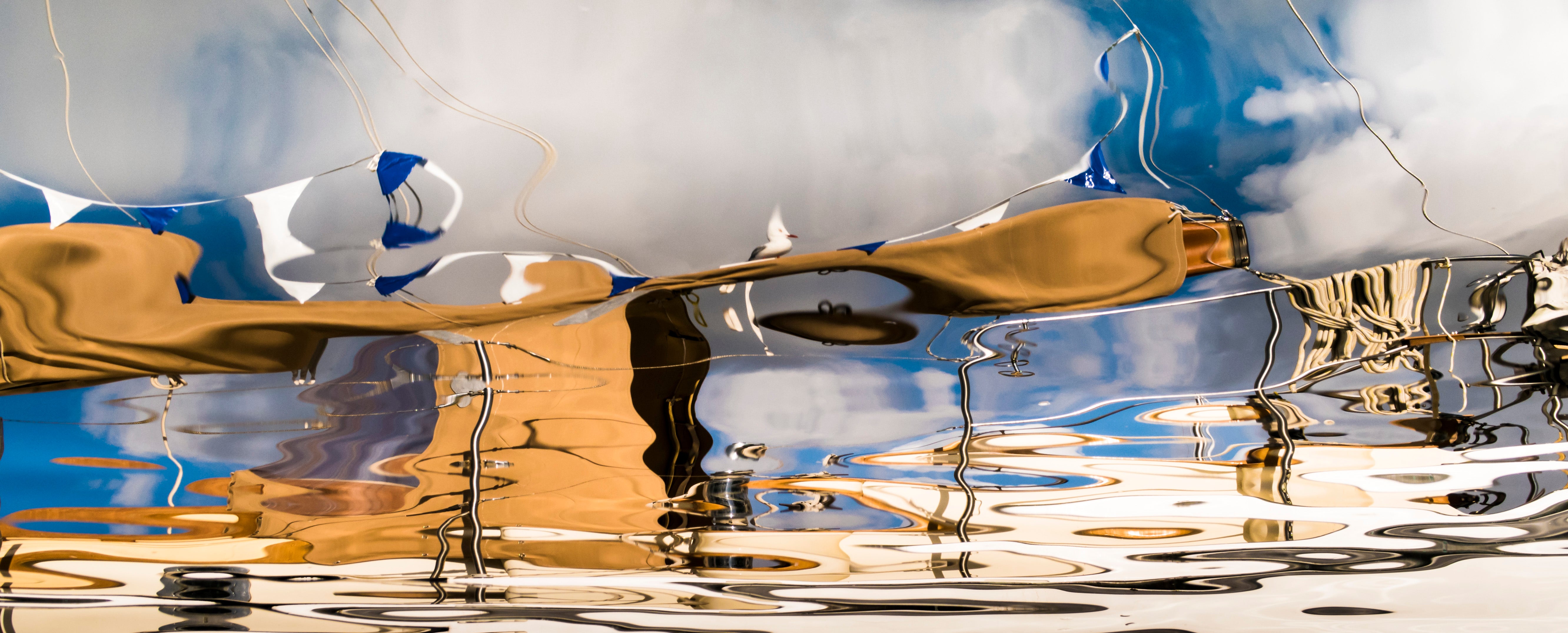 Reflective surface with gold object and blue sky with clouds.