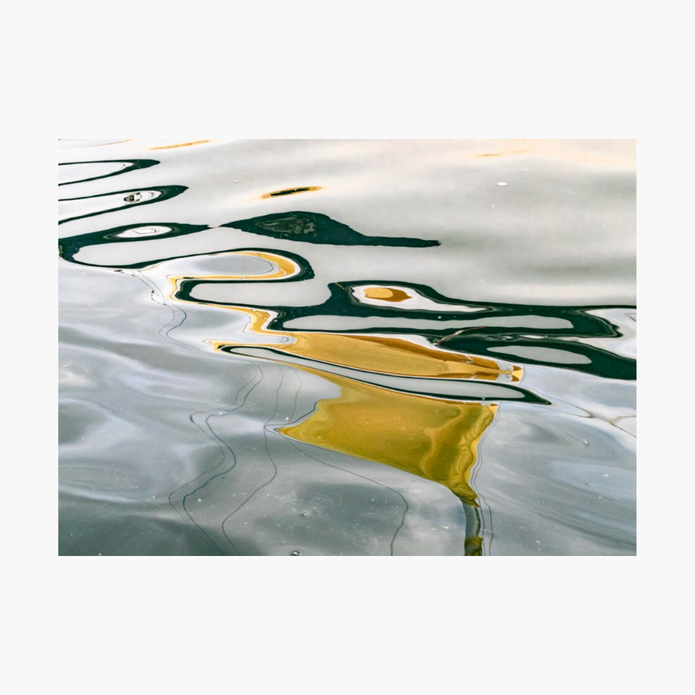 Abstract water reflection print featuring wavy lines of dark green, black, and golden yellow on a muted grey-blue surface, presented with a white border.